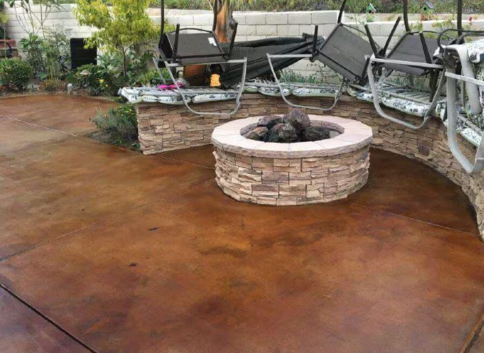 Acid stained concrete patio with a stone fire pit and seating wall